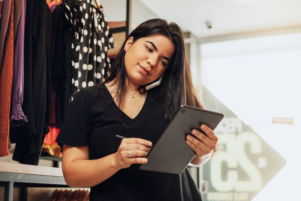 Office Management Frau telefoniert mit Handy und erledigt zugleich Aufgaben auf dem Tablet 